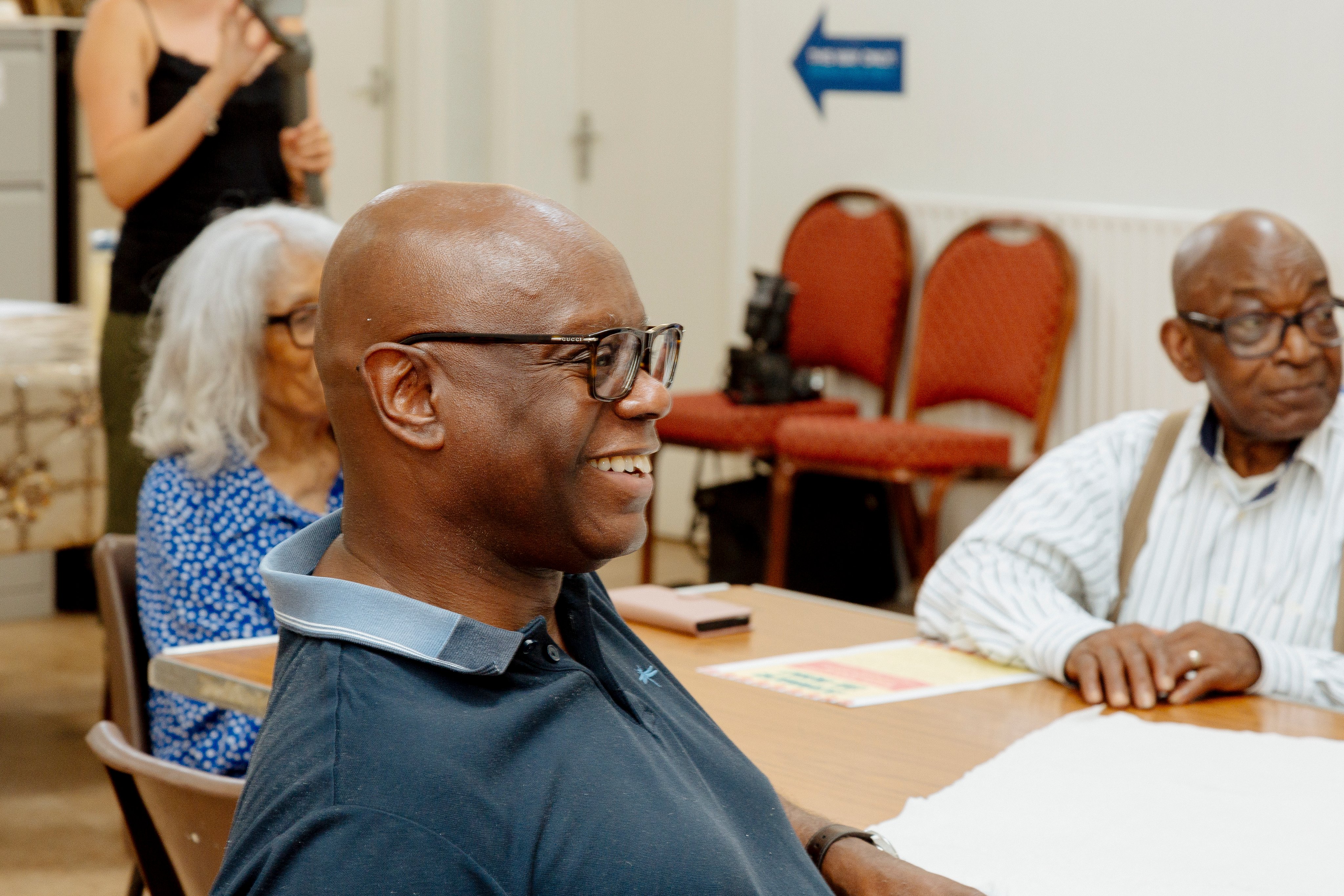 Older people sat round table in community space