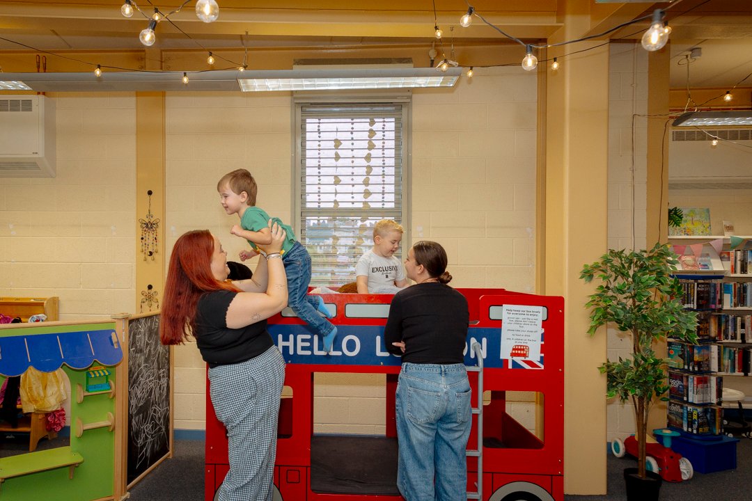 Two women and their two children playing in a community space, smiling. 