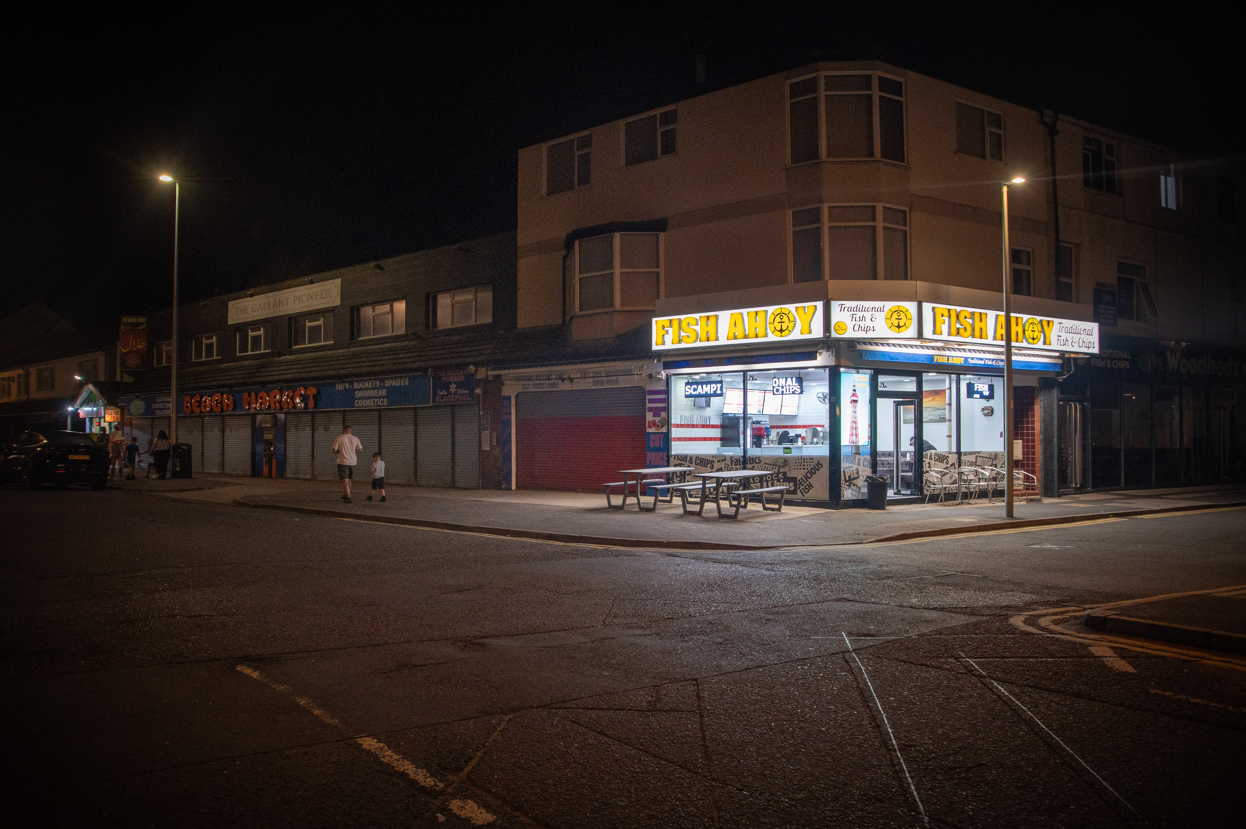 A chip shop lit up on a street corner at night in South Shore Blackpool
