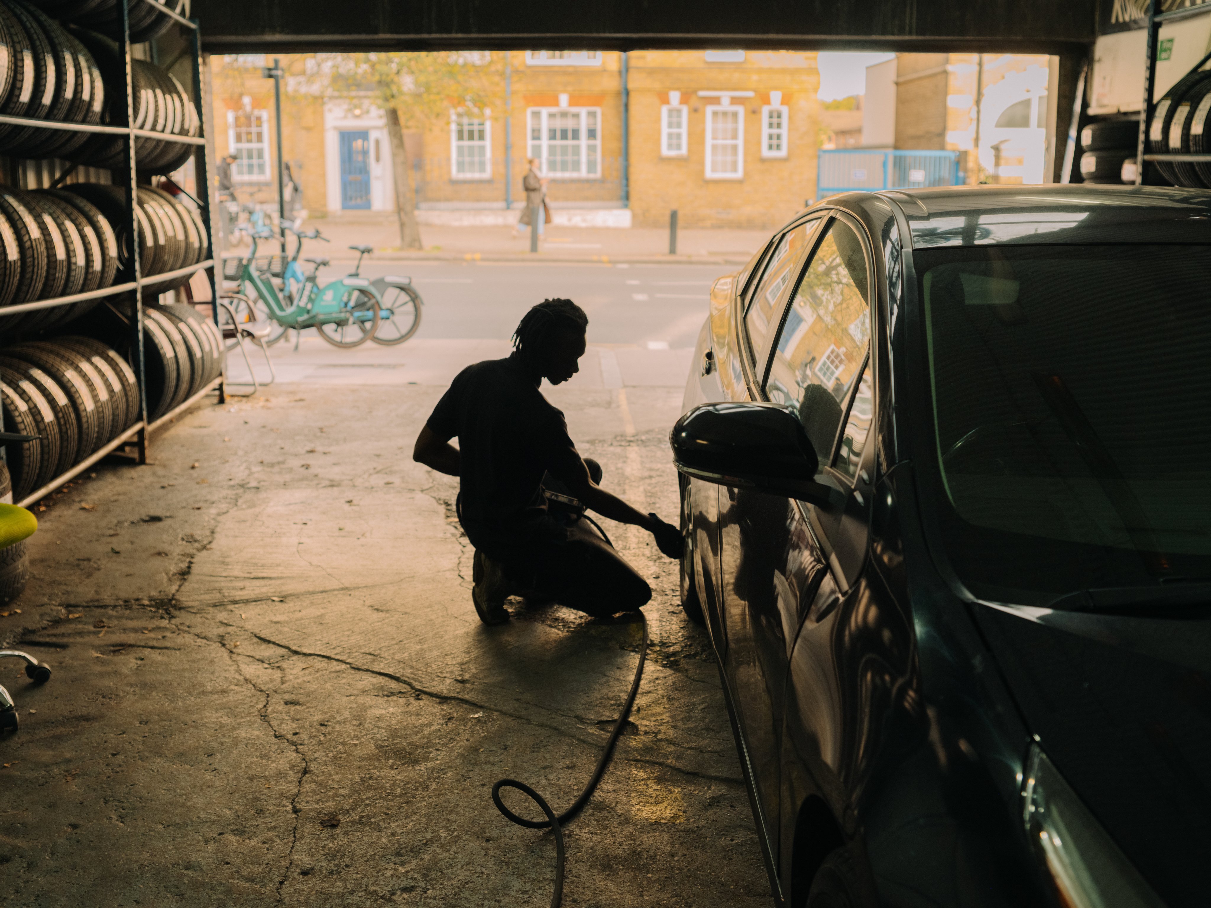 Mechanic at work in a garage looking out onto street.