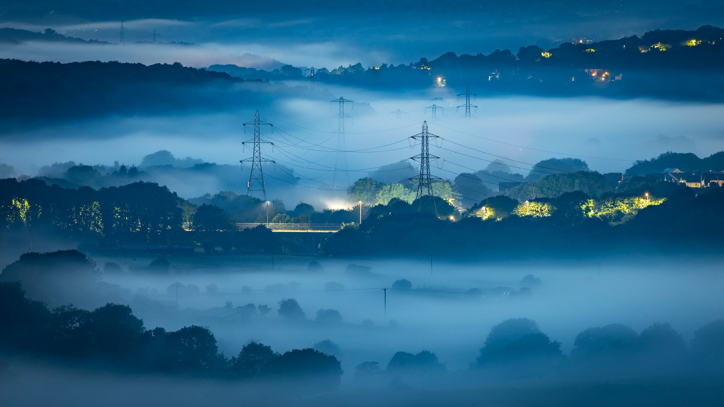 Misty valley in Leeds, Yorkshire with electricity pylons