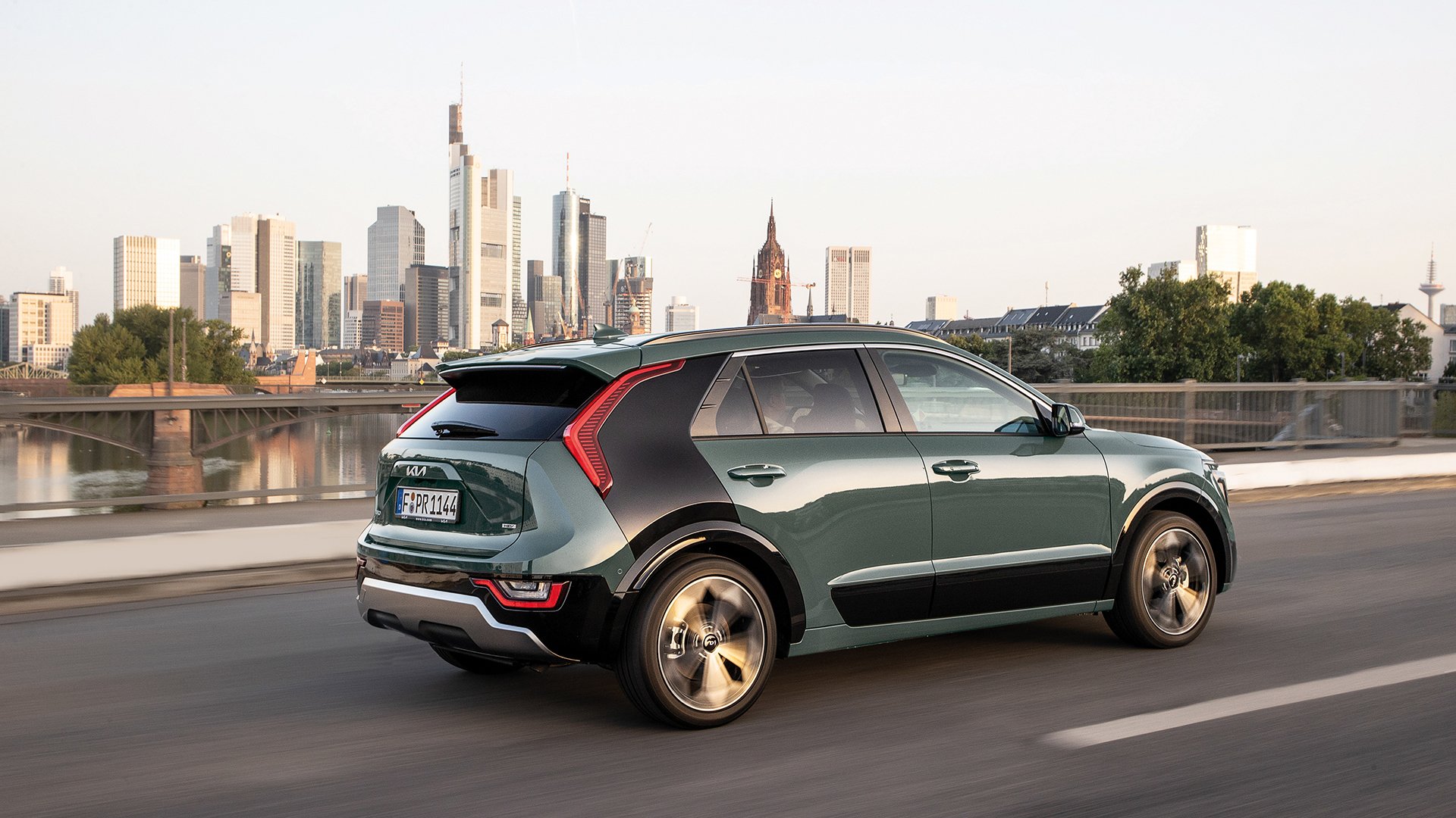Kia Niro side profile driving with a city skyline behind