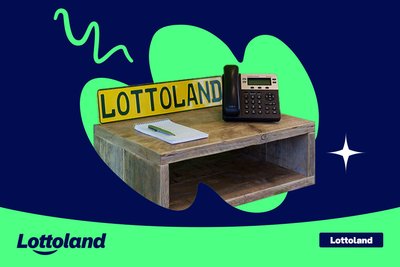 Desk with a phone, notepad, and Lottoland sign. 