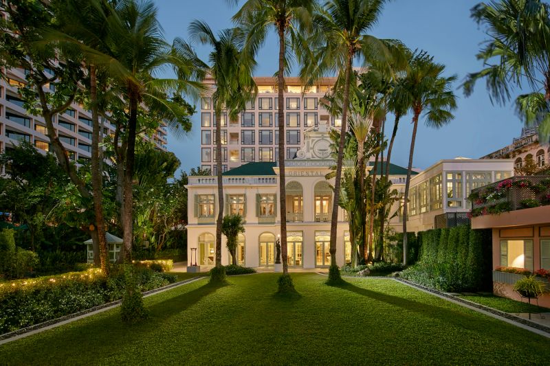 Mandarin Oriental Bangkok - Colonial-style exterior lit at dusk, framed by palm trees
