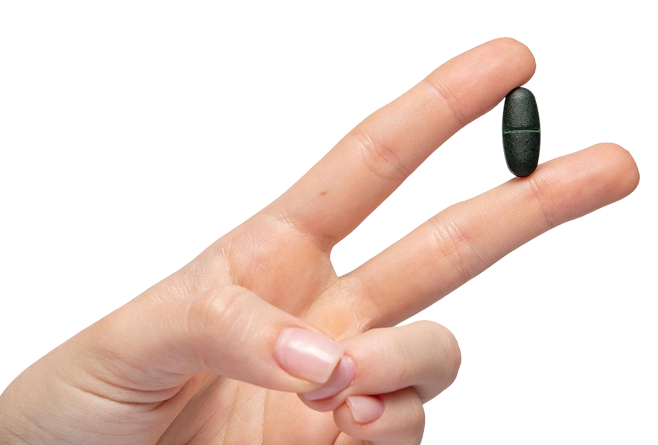 Two fingers holding a green PhytoMulti multivitamin tablet on a dark blue background, representing a daily wellness habit as you reset your routine.