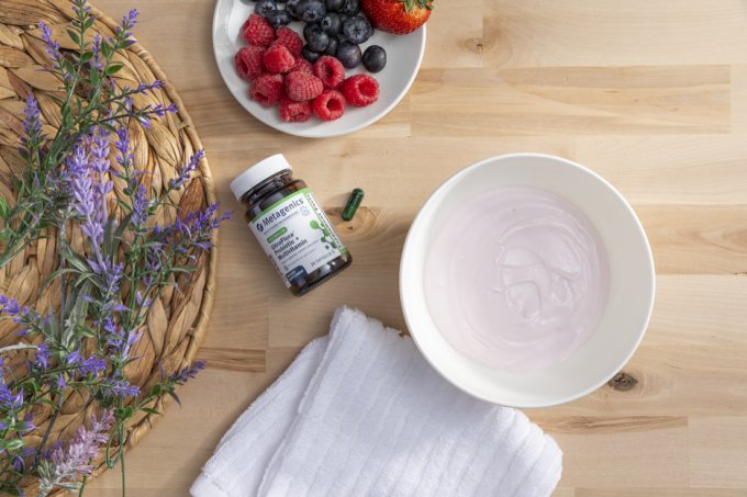An overhead photograph of a table with a selection of fresh berries, a bowl of yoghurt and a Metagenics probiotic supplement