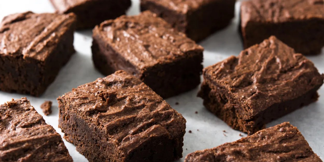 A close up of a selection of sliced brownie squares on parchment paper