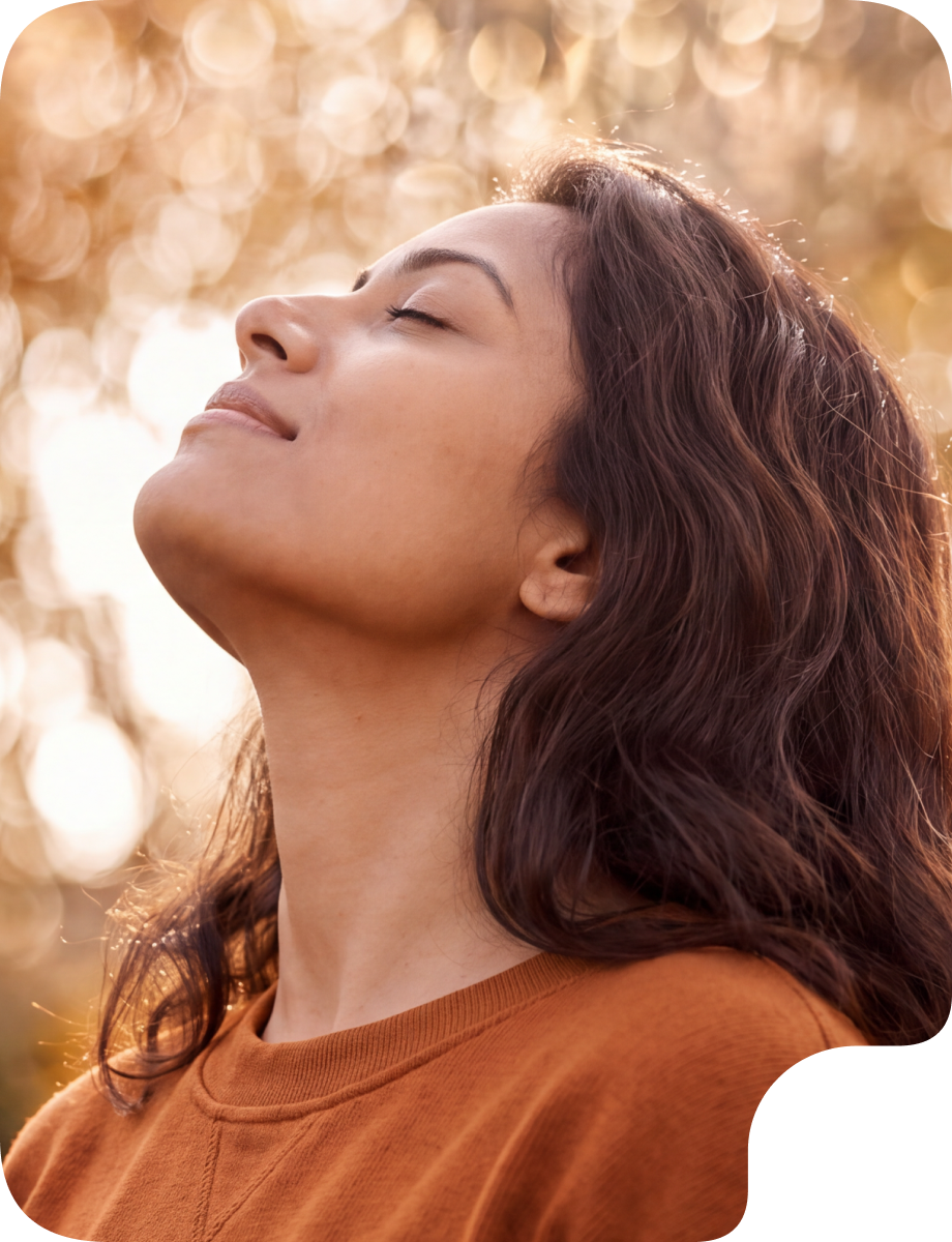 Woman outdoors looking upward with sunlight in the background, representing immune health and seasonal wellness.