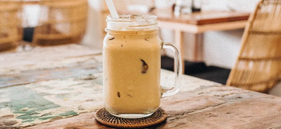 Closeup of a iced smoothie in a mason jar on a table in a cafe