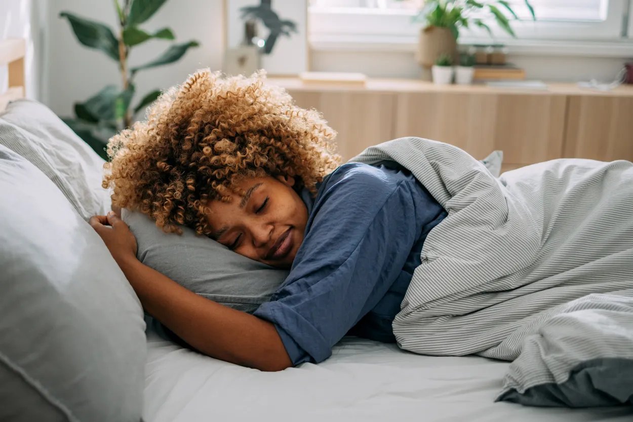 A smiling African American woman asleep in her bed