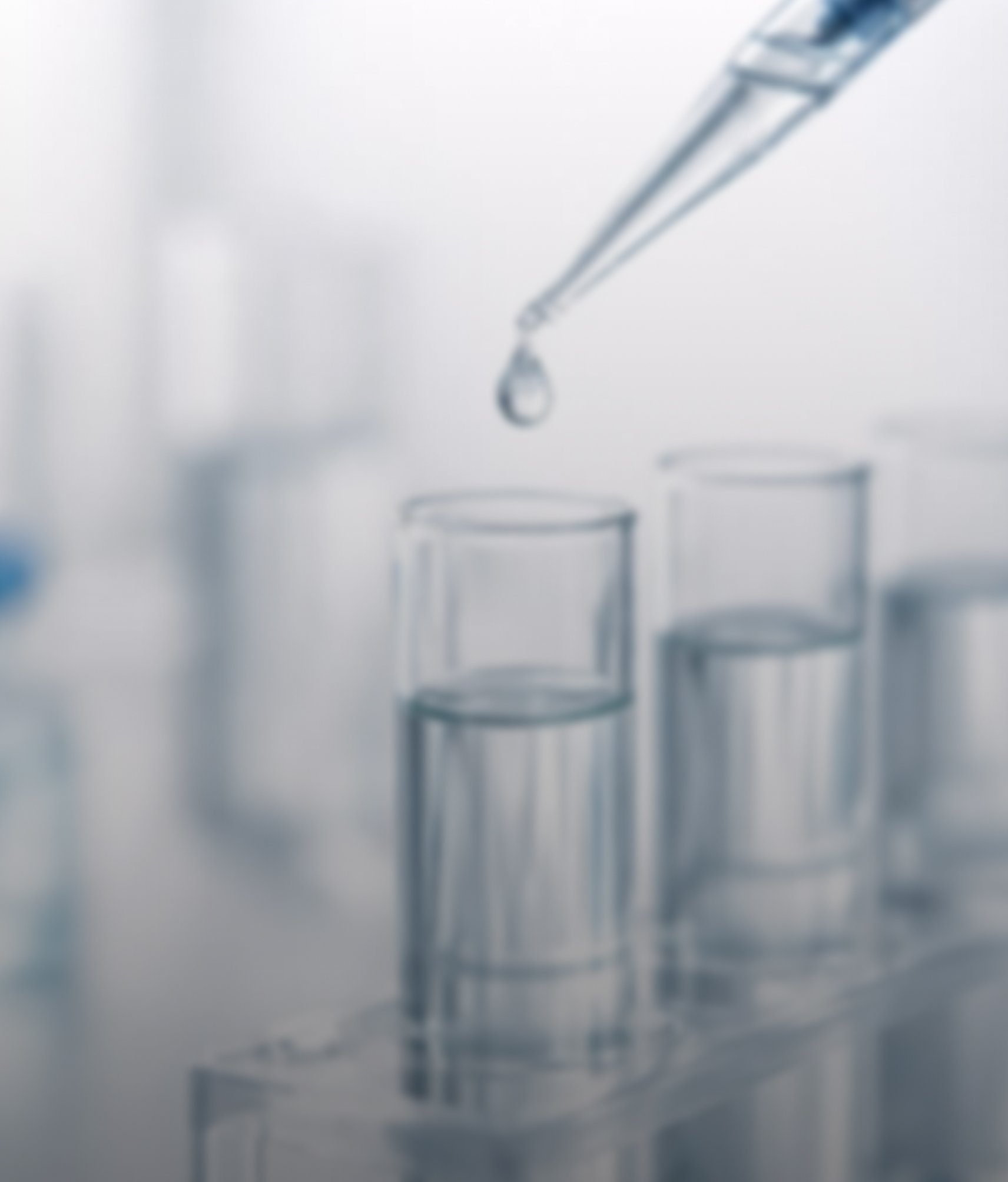 Laboratory pipette dispensing liquid into a test tube above scientific glassware