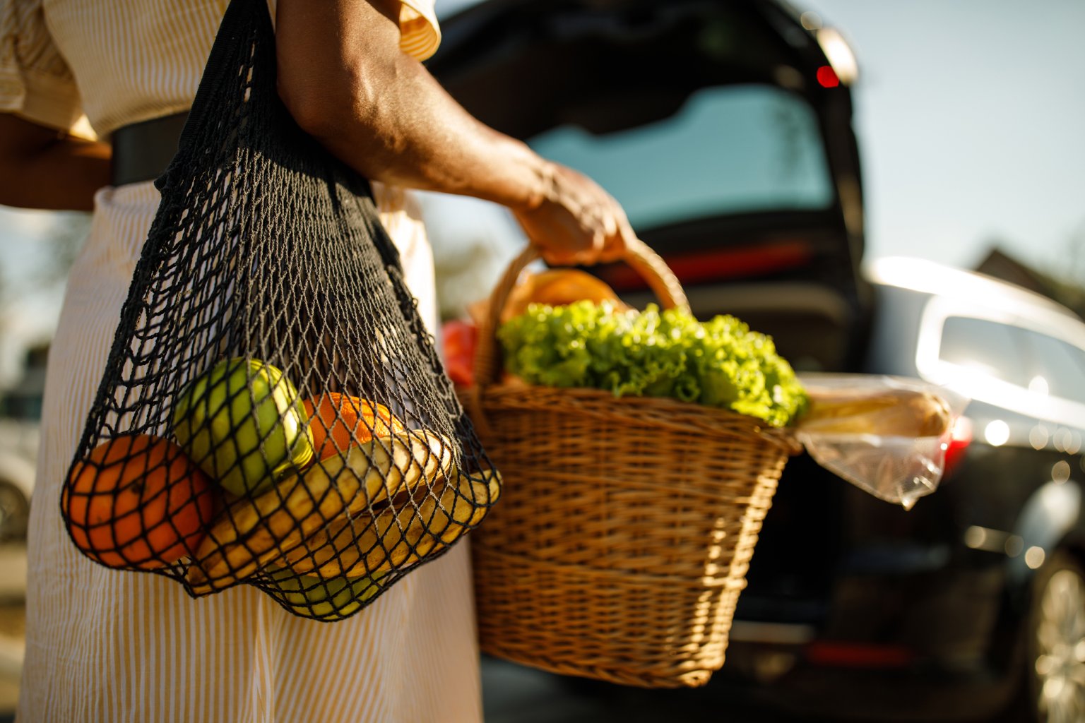 Cropped image of a woman walking to her car after a shopping trip with bags of fresh produce