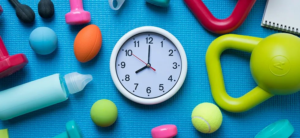 Overhead image of an array of exercise equipment on an exercise mat with a clock.