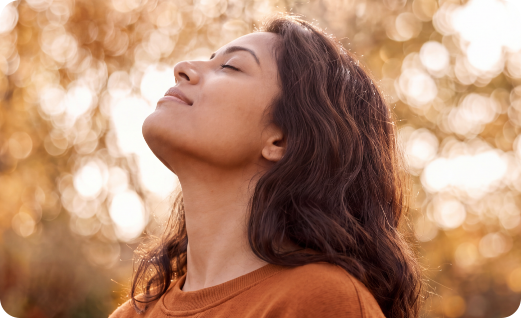 Woman outdoors looking upward with sunlight in the background, representing immune health and seasonal wellness.