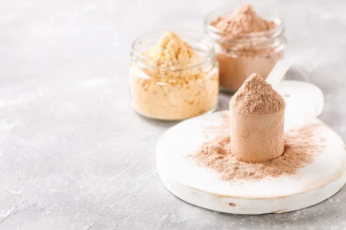 Scoops and jars of powdered nutritional formula on a light surface.