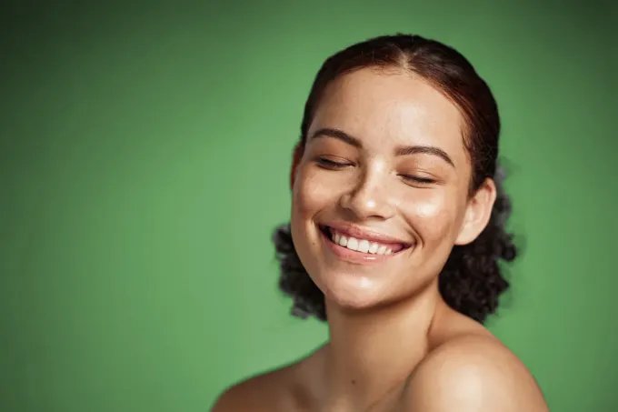 A happy, smiling woman against a green background
