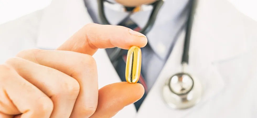 Closeup of a doctor in a white coat holding a Omega 3 capsule