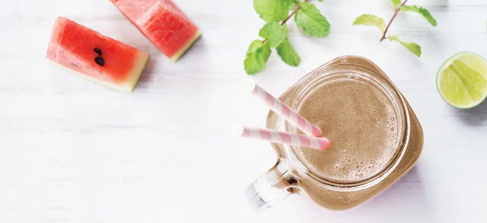 An overhead photograph of a watermelon smoothie with lime and mint on the table