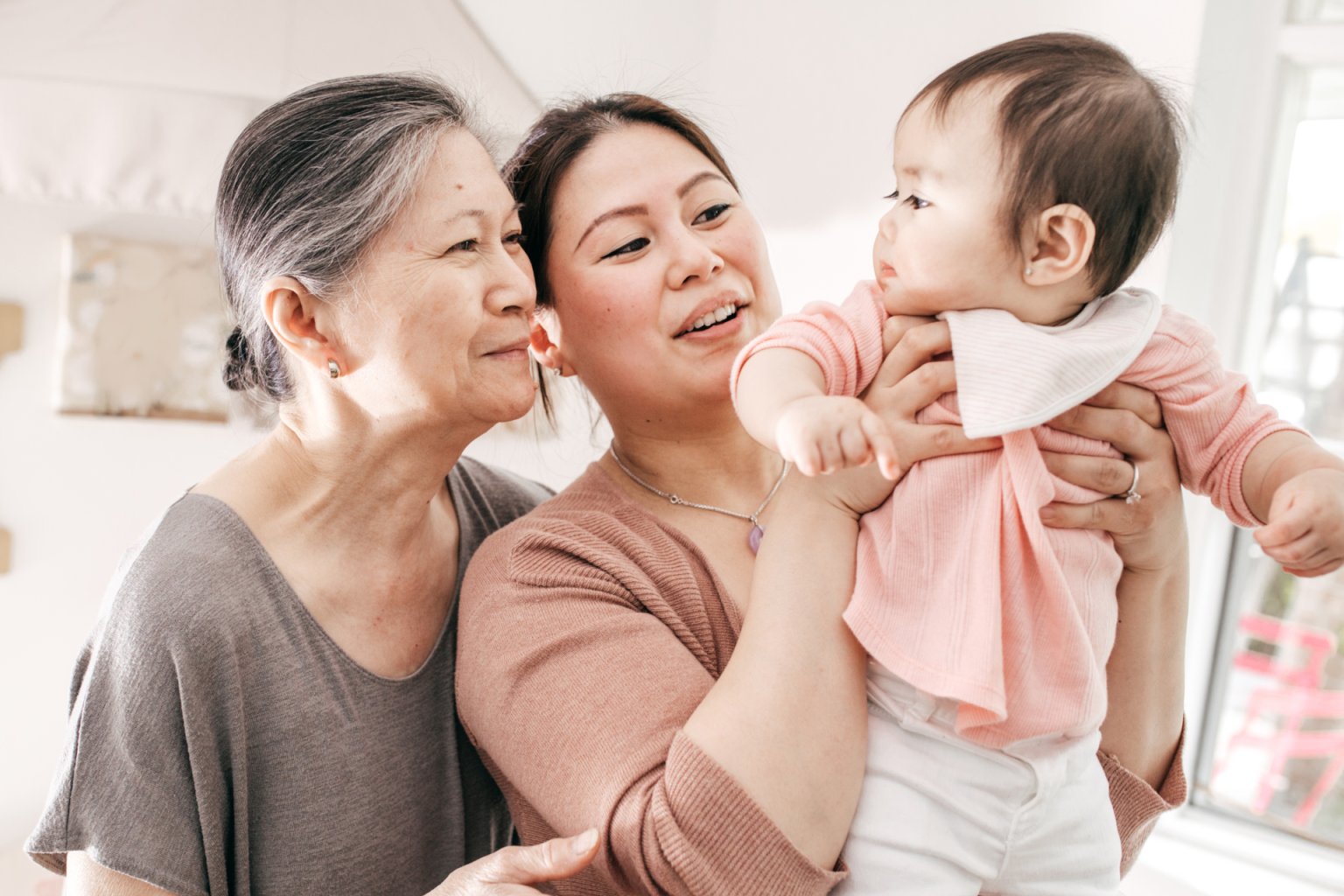 A family group of a grandmother, mother and her baby in a home setting