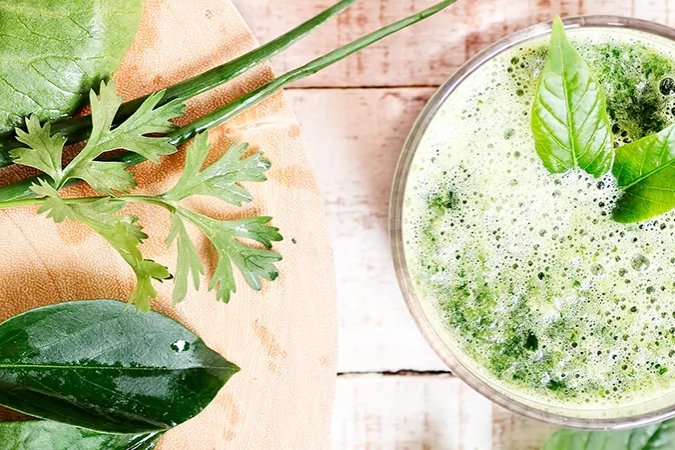 Green detox smoothie with fresh leafy greens, herbs, and lemon.