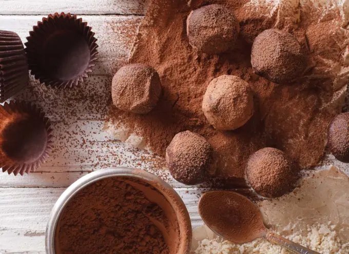 A selection of keto-friendly truffles drenched in cocoa powder on a white tabletop