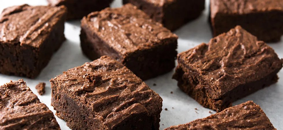 A close up of a selection of sliced brownie squares on parchment paper