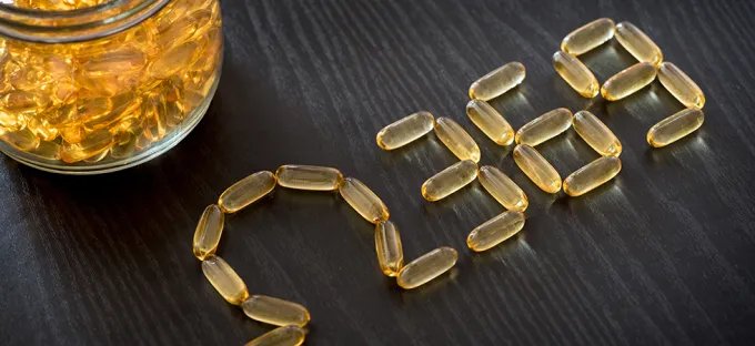 A glass jar of capsules with and then several on the table spelling out the Greek letter Omega, and the numbers 3, 6 and 9