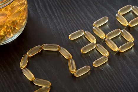 A glass jar of capsules with and then several on the table spelling out the Greek letter Omega, and the numbers 3, 6 and 9