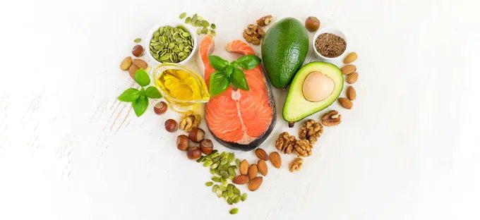 A selection of foods for healthy cholesterol, including salmon, walnuts, almonds, hazel nuts, pumpkin seeds, avocado and olive oil
