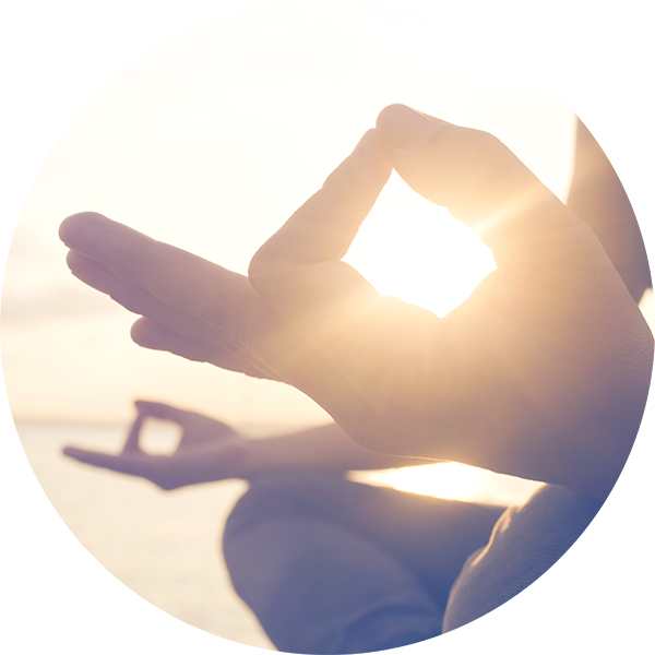 Close up of the sun shining through a woman's encircled thumb and forefinger as she practices yoga