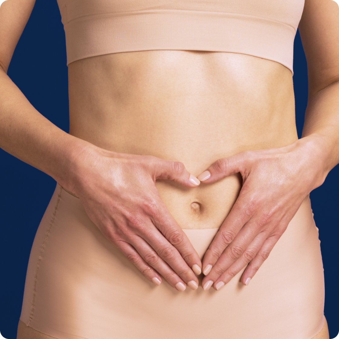 Close-up of a person’s midsection wearing neutral-colored activewear, with both hands gently forming a heart shape over the lower abdomen to represent digestive and gut health. The image supports Metagenics messaging around wellness, encouraging users to reset your routine during the new year supplement sale.