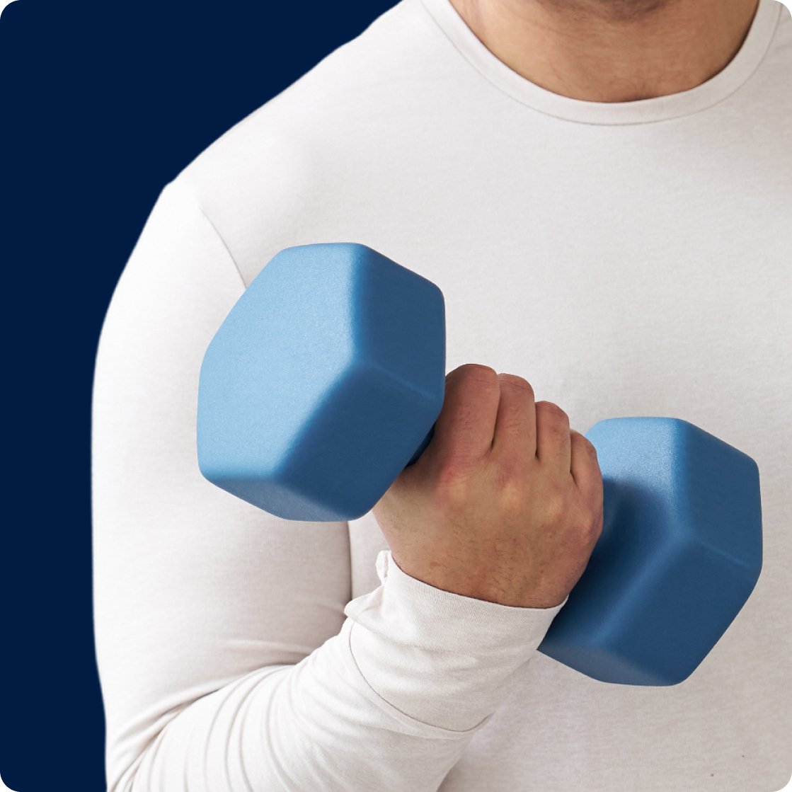 Close-up of a person wearing a white long-sleeve top holding a blue dumbbell at chest level, symbolizing strength, mobility, and physical vitality. The image represents the body that keeps you moving, aligning with Metagenics wellness support to reset your routine during the new year supplement sale.