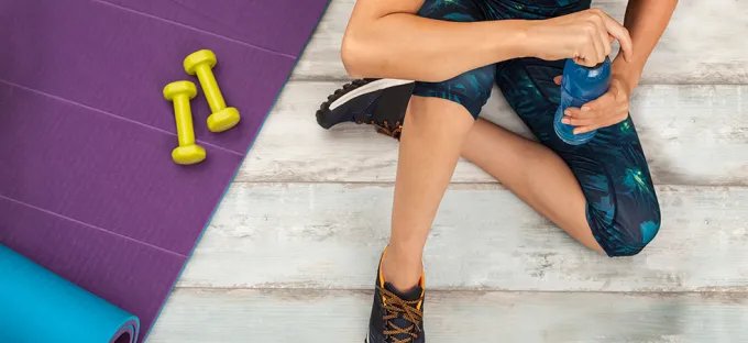 Overhead image of a woman take a break from exercise to drink from her water bottle.
