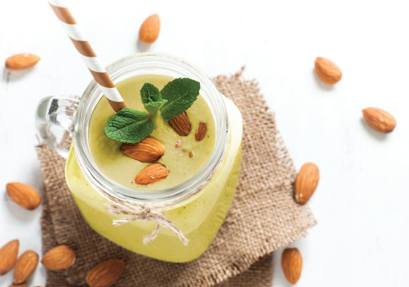 Overhead closeup image of a smoothie in a glass garnished with almond nuts