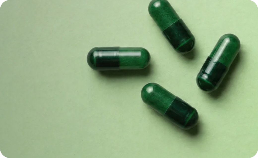 Green supplement capsules arranged on a light green background, representing digestive and gut health support.
