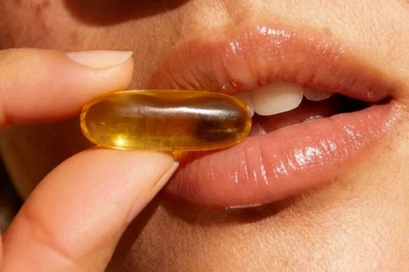 Closeup of woman taking omega-3 softgel