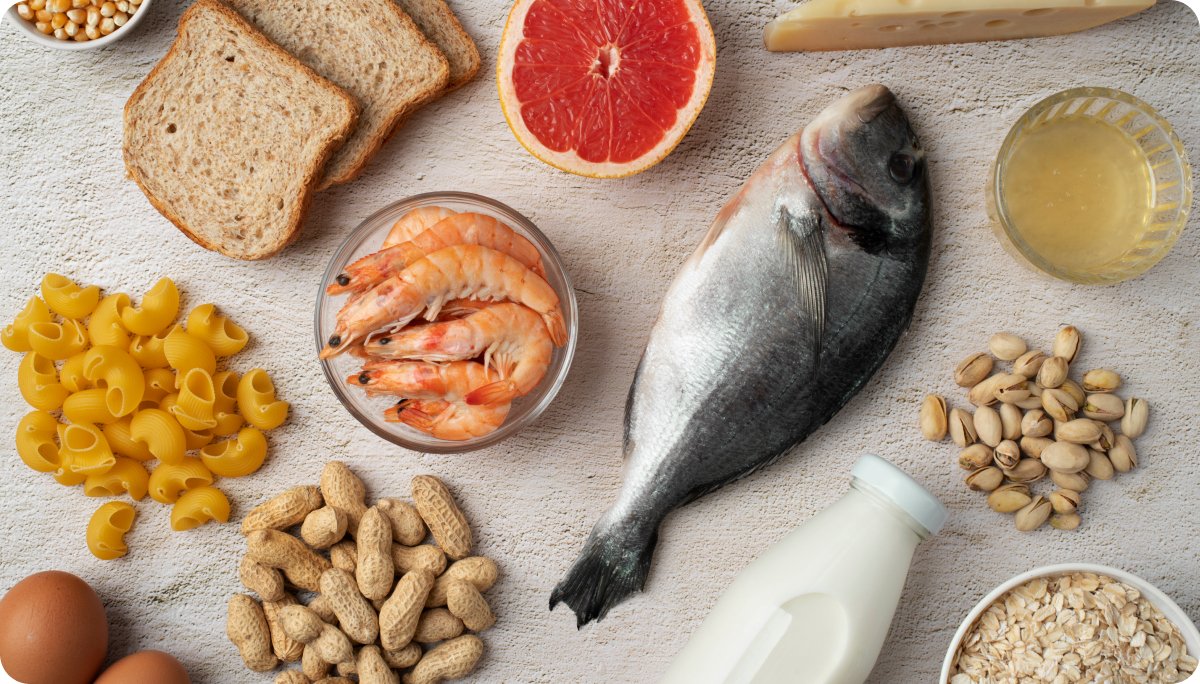 Assortment of omega-3 rich foods including fish, shrimp, eggs, milk, nuts, seeds, pasta, bread, and grapefruit, illustrating sources of EPA and DHA.