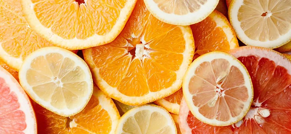 Sliced oranges, lemons, and grapefruit arranged in a colorful citrus background.