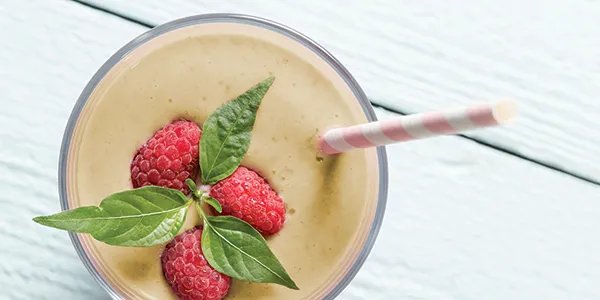 Overhead closeup of a green smoothie garnished with fresh raspberries