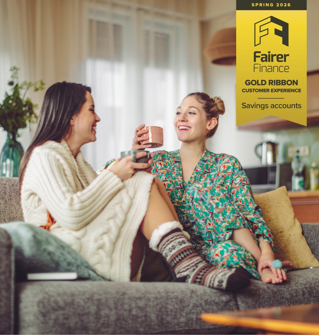 Two young women in loungewear drinking tea at home.