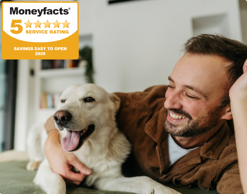 Photo of a man cuddling with his dog in the living room of their house.