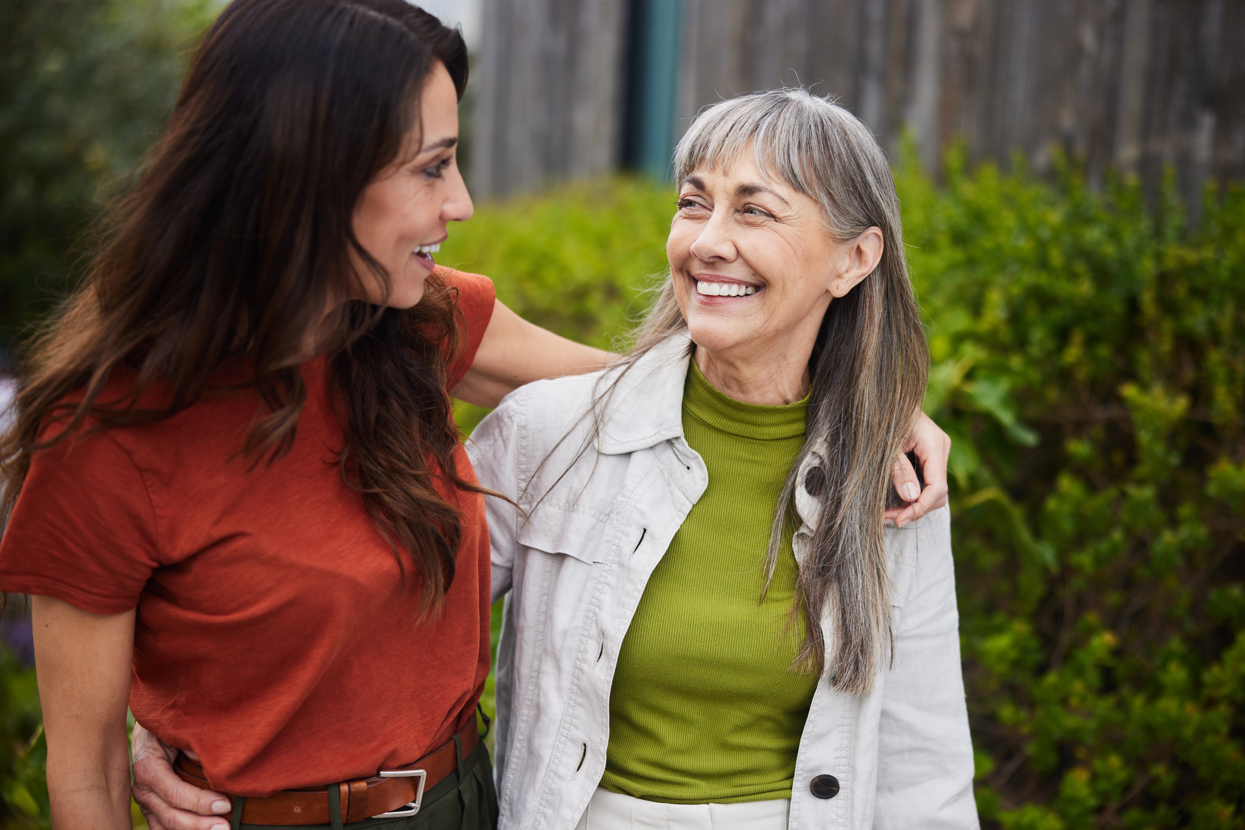 Smiling senior woman and her daughter walking outside together