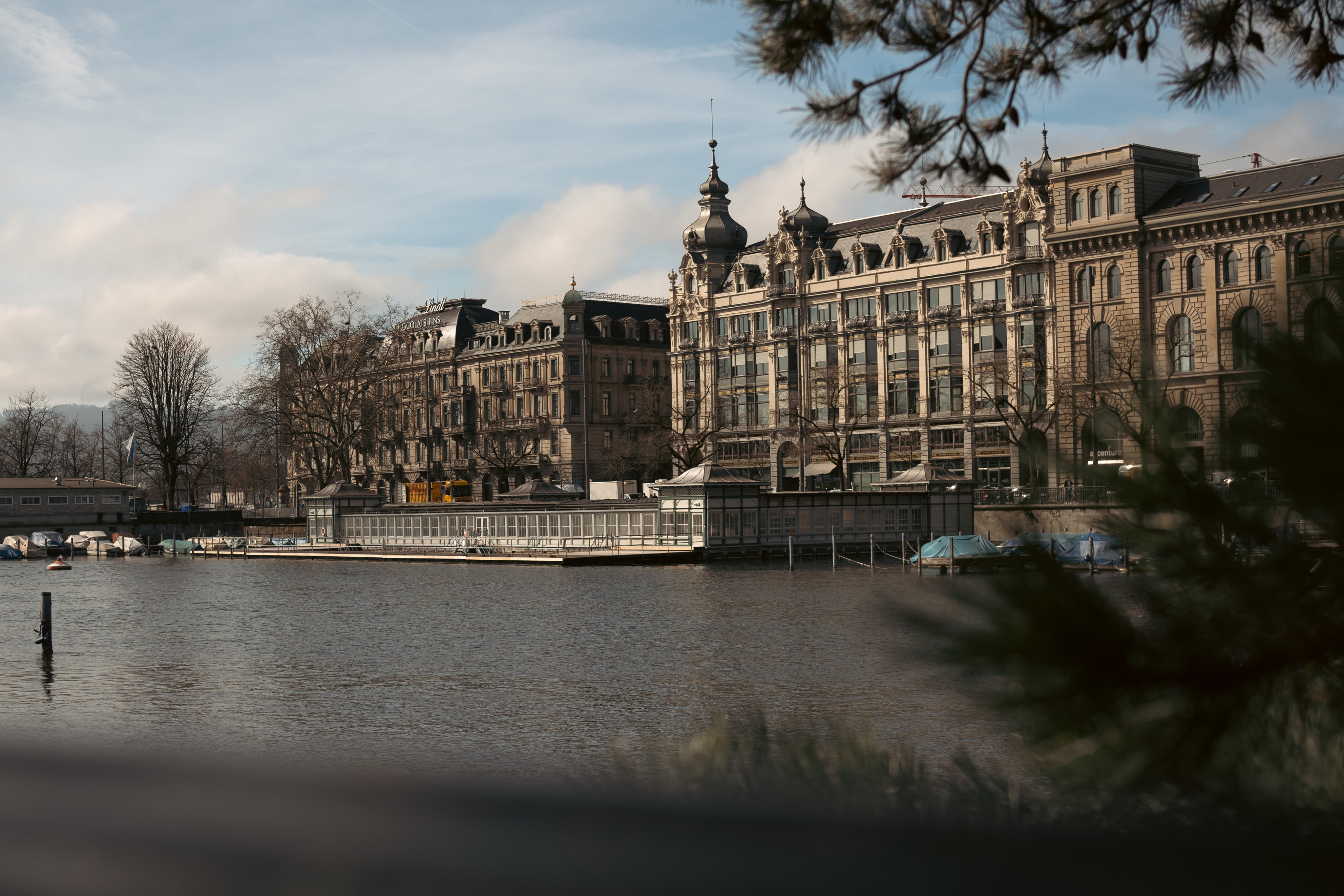 Le long de la rivière se trouve un long bâtiment plat avec un ponton flottant sur lequel on peut se promener. Des bateaux sont amarrés autour.  