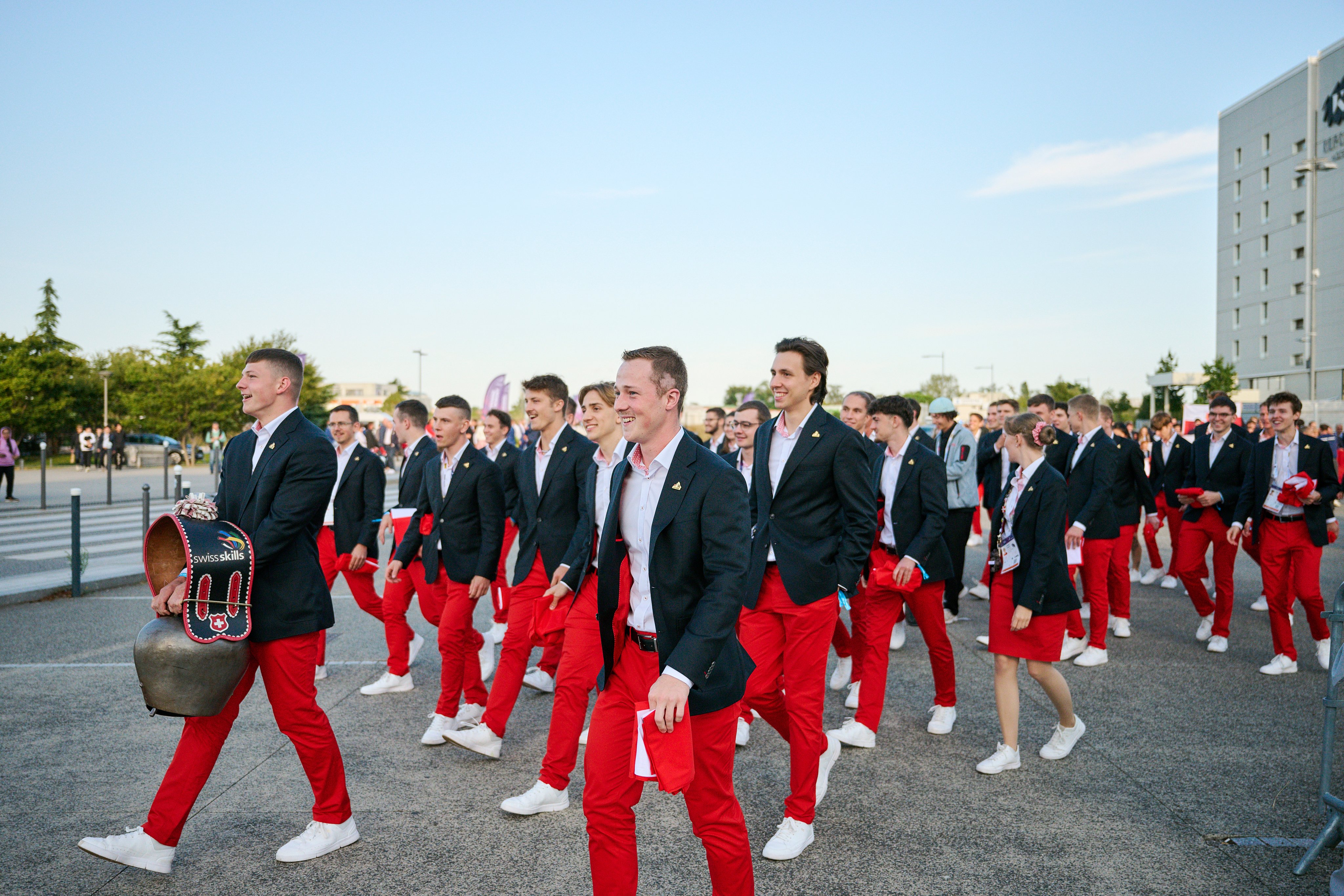 Des jeunes gens vêtus de pantalons rouges et de vestes de costume bleues marchent ensemble.