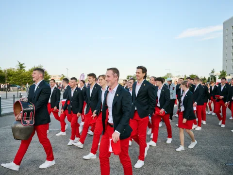 Des jeunes gens vêtus de pantalons rouges et de vestes de costume bleues marchent ensemble.