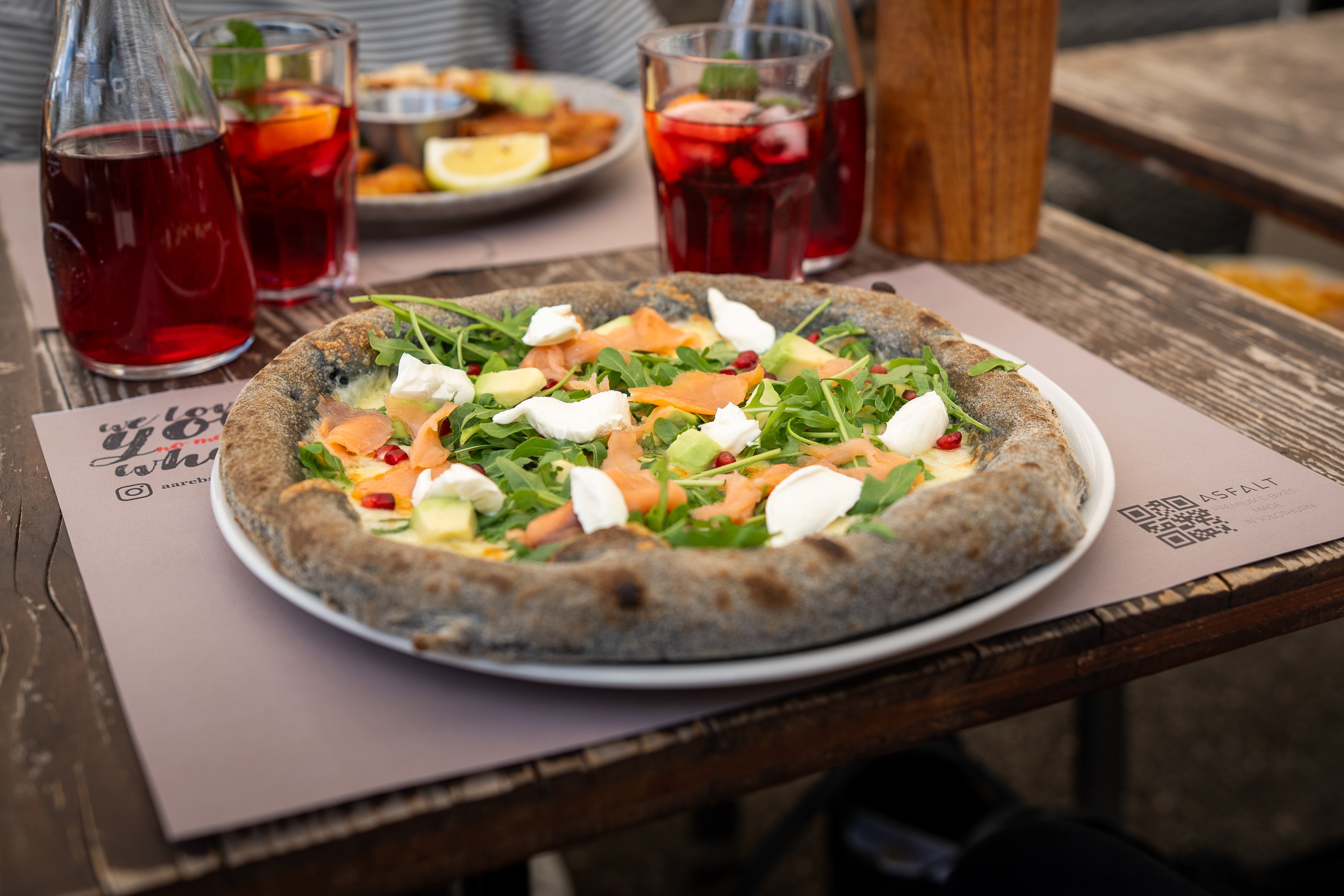 Eine Pizza mit dickem Rand auf einem gedeckten Tisch im Freien.