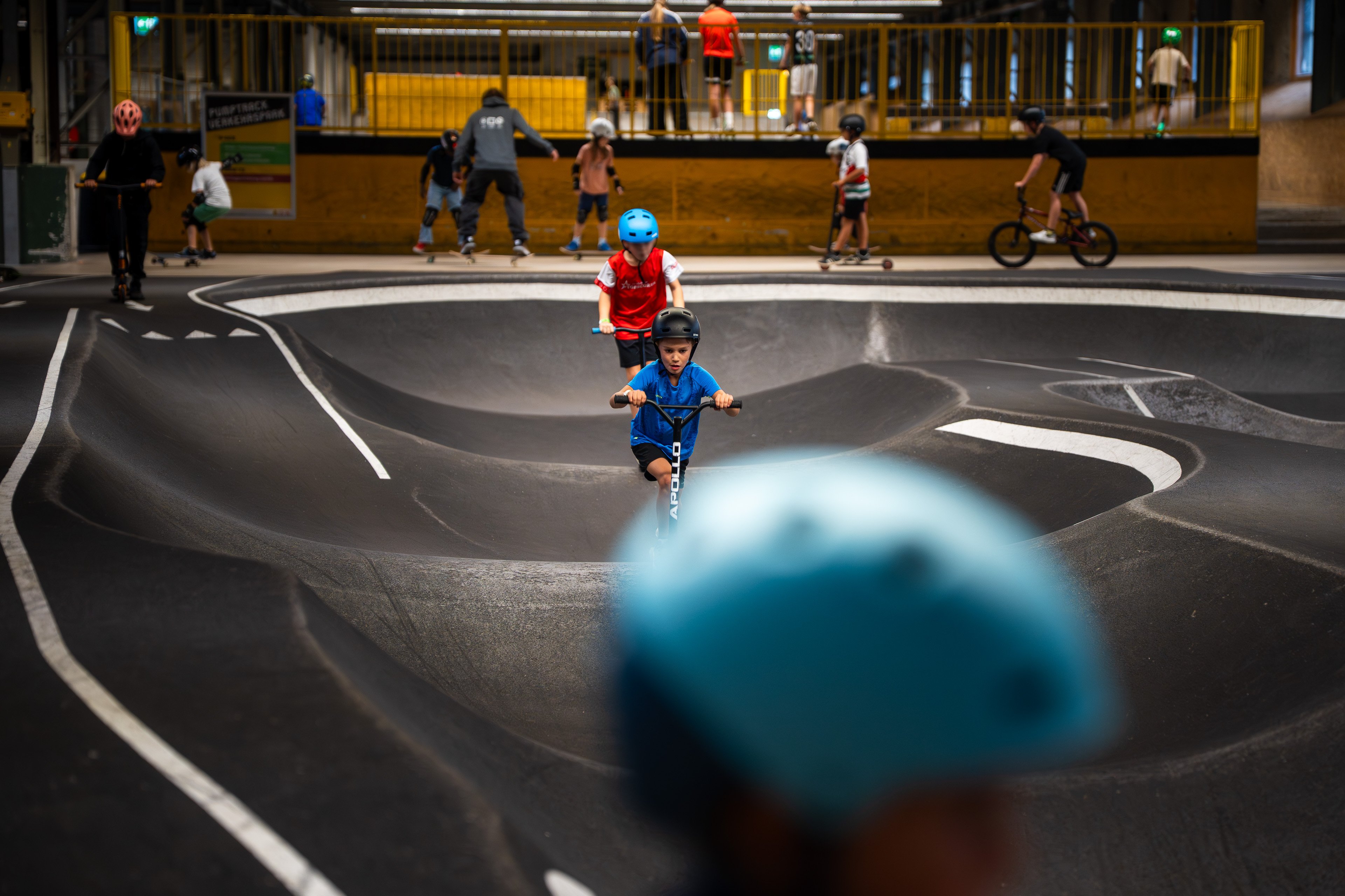 Kinder mit Helm auf dem Trottinett im Skills Park. 
