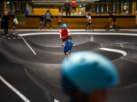 Kinder mit Helm auf dem Trottinett im Skills Park.
