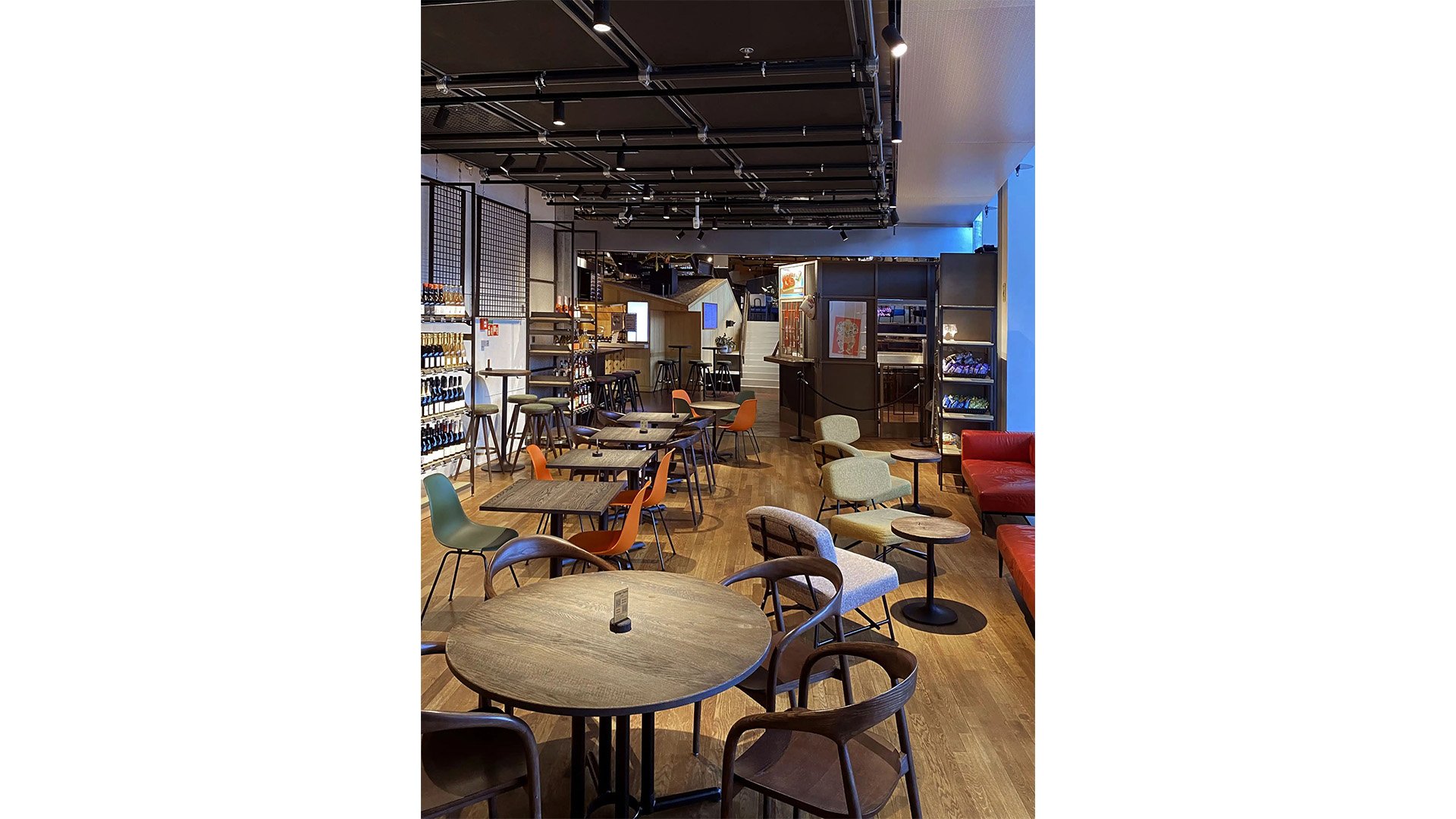 Il Bar Beer & Wine Shop con tavoli e sedie, e scaffali a parete pieni di bottiglie di vino.