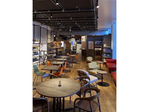 Il Bar Beer & Wine Shop con tavoli e sedie, e scaffali a parete pieni di bottiglie di vino.